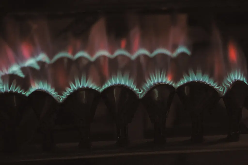 Rampe de brûleurs à gaz allumée dans la pénombre, flammes bleues au ras des brûleurs