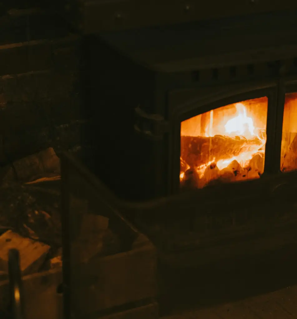 Poêle à bois en fonte à deux portes vitrées, allumé le soir dans une pièce sombre