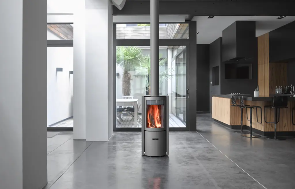 Poêle à bois Stûv 30-compact allumé au centre d'un loft ouvert sur la cuisine