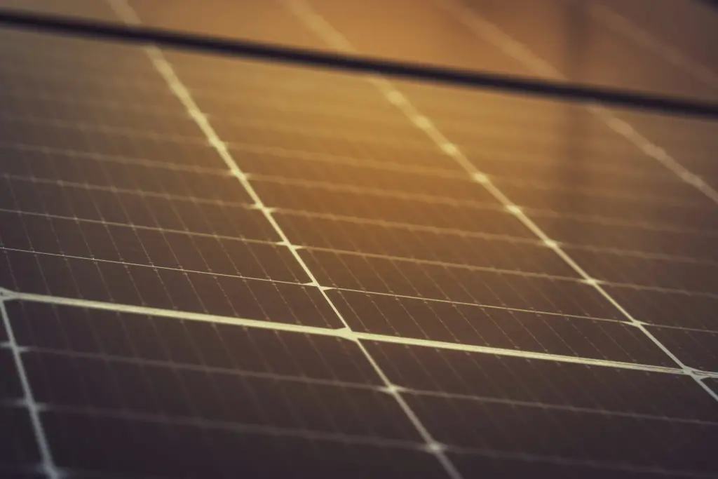 Gros plan des cellules d'un panneau photovoltaïque, reflet du soleil bas sur le verre