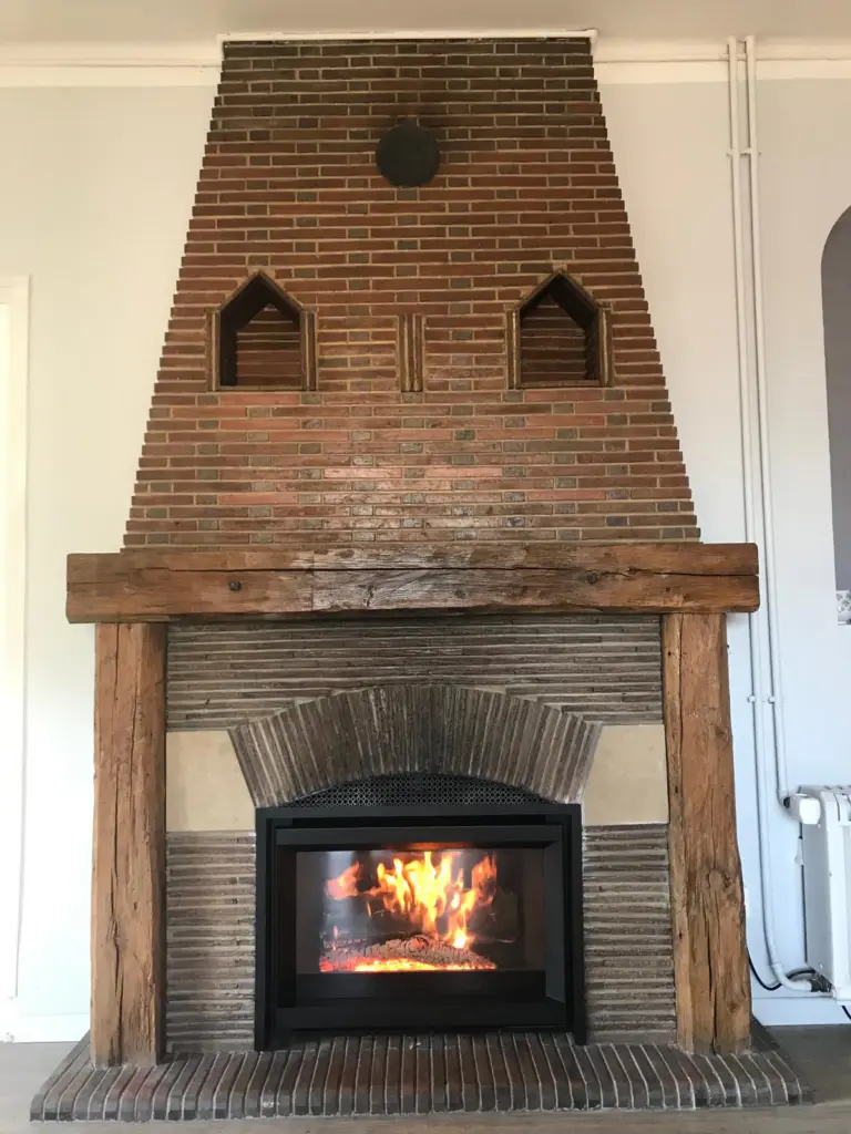 Insert à bois allumé dans une cheminée en briques à poutre de bois