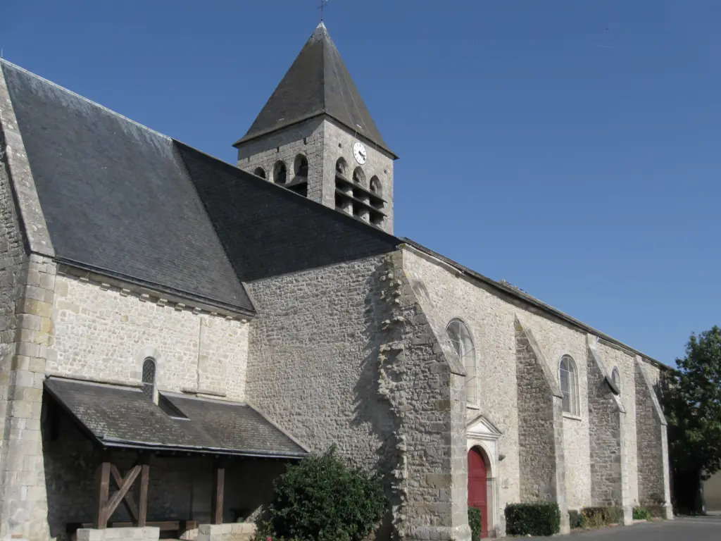 L’église Saint-Georges de Bou, ses murs de pierre et son clocher à horloge, sous un ciel bleu.