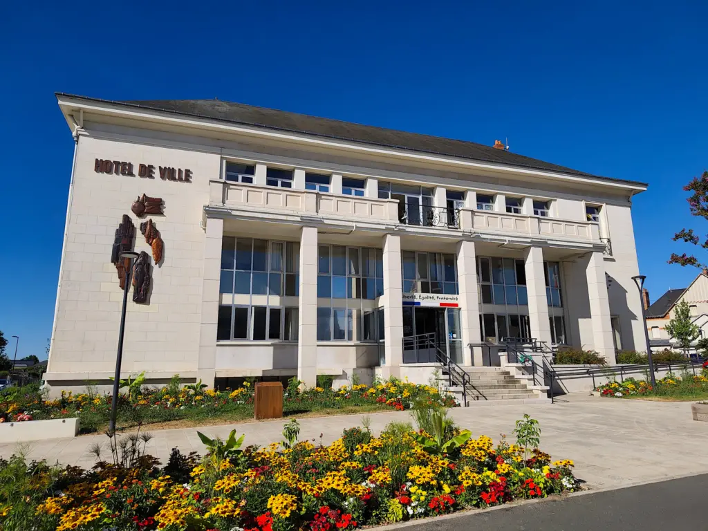 L’hôtel de ville de Saint-Jean-de-la-Ruelle derrière des massifs de fleurs jaunes et rouges.